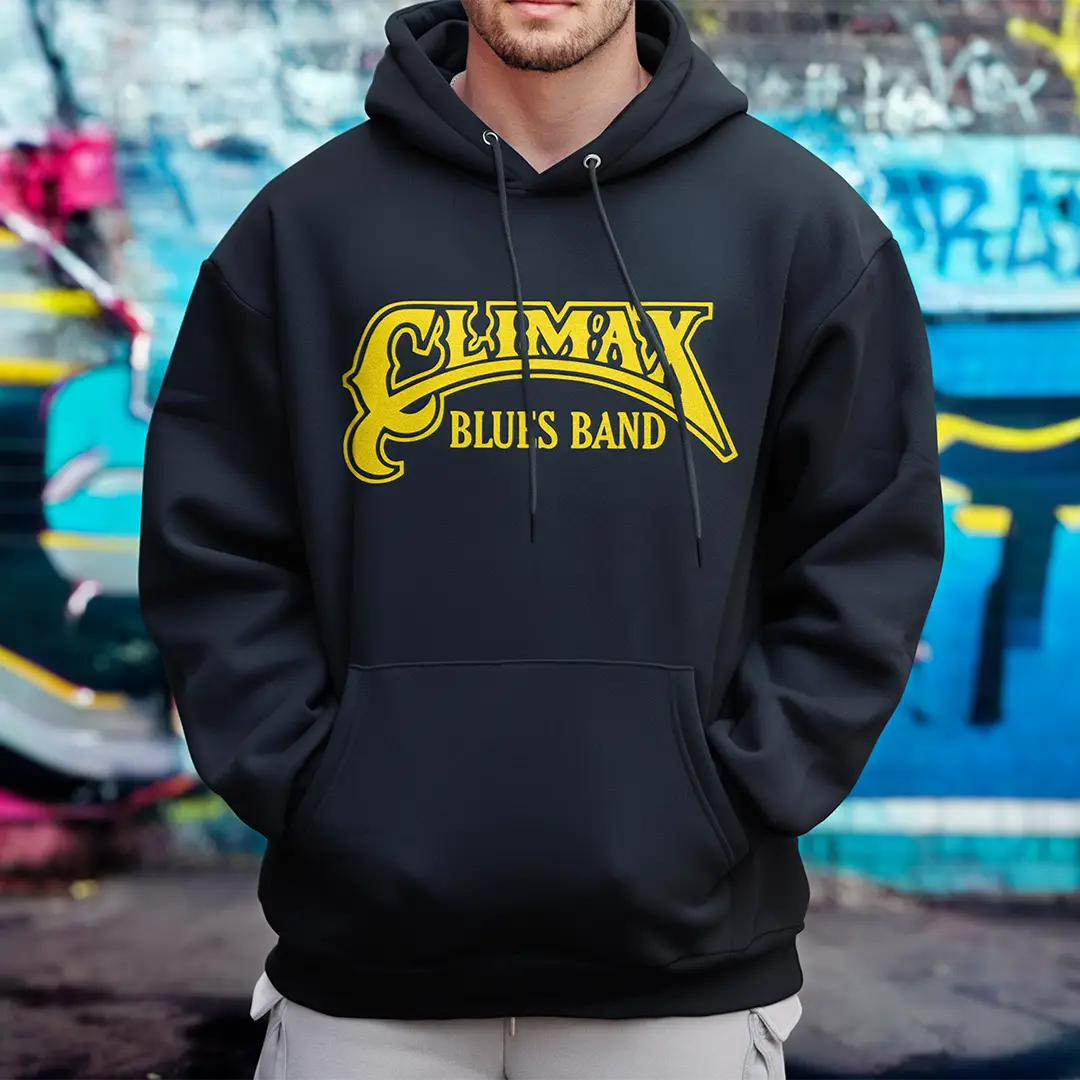 man wearing black hoody with gold climax blues band logo standing infant of colourful wall